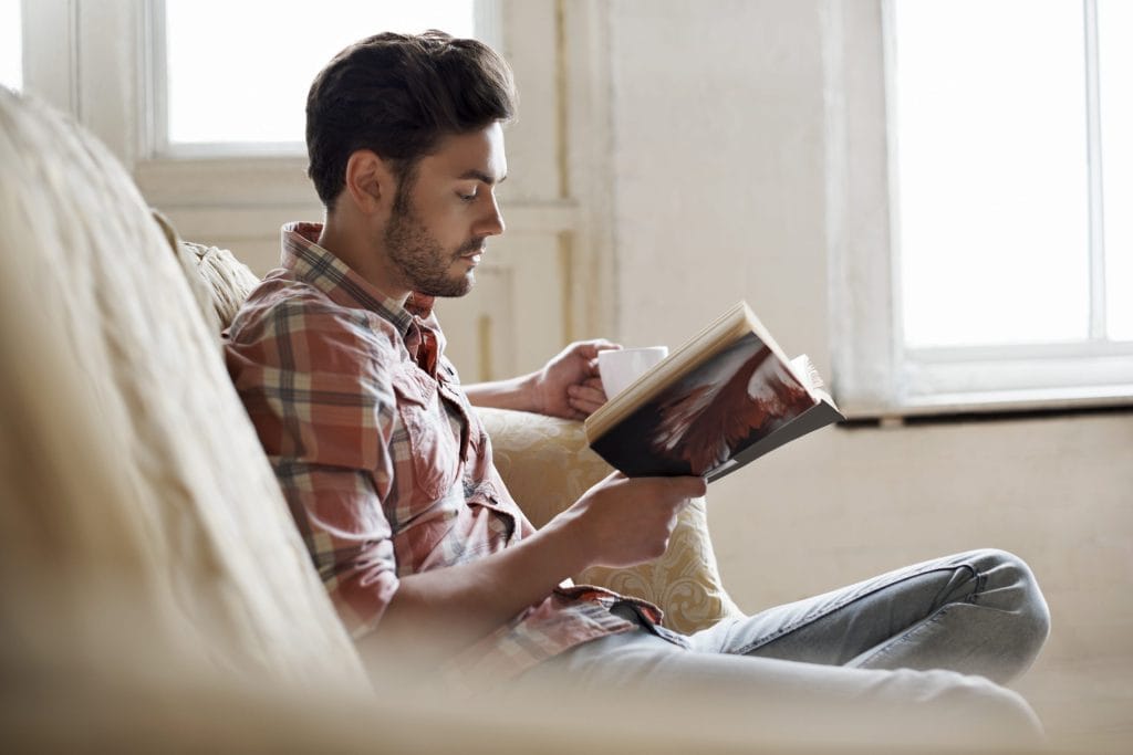 Man reading book on sofa scaled 1